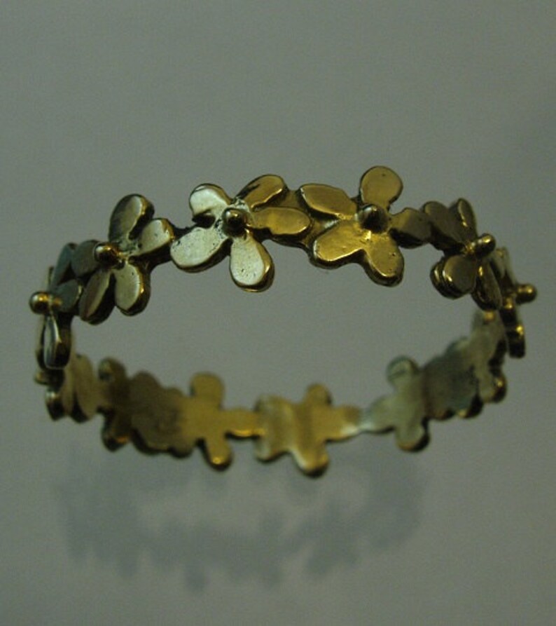 Peut inclure: Une bague en or avec un motif de petites fleurs autour de la bande.