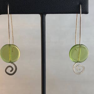 May include: A pair of silver earrings with green glass circles and a silver swirl design.