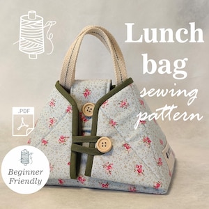 Könnte beinhalten: Eine hellblaue, gesteppte Lunchtasche mit floralem Muster und grünen Zierleisten. Die Tasche hat einen beigen Griff und wird mit Holzknöpfen verschlossen. Der Text auf dem Bild lautet "Lunch bag sewing pattern" und "Beginner Friendly."