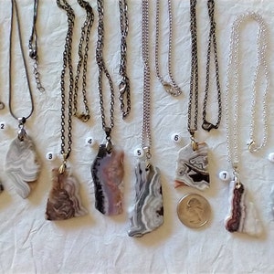 May include: Eight agate slice pendants on chains, each with unique patterns of white, brown, and black. The pendants are numbered 1 through 8.