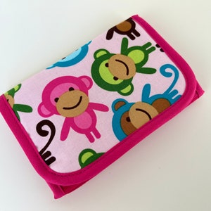 Op de afbeelding: Roze stoffen portemonnee met een roze, groene, blauwe en bruine aapjesprint. De portemonnee heeft een roze rits.