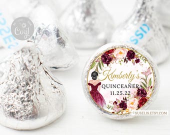 May include: A silver foil-wrapped chocolate candy with a circular sticker featuring a floral wreath, a butterfly, and an illustration of a person in a dark red dress. The text reads Kimberly's QUINCEAÑERA 11.25.22 and SUSELIS.ETSY.COM.