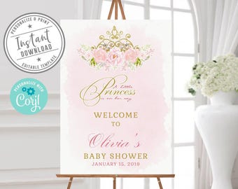 Puede incluir: Un letrero rectangular vertical sobre un caballete de madera con fondo de acuarela rosa, una ilustración de corona dorada con flores rosas y el texto A little princess is on her way, WELCOME TO Olivia's BABY SHOWER JANUARY 15, 2019.