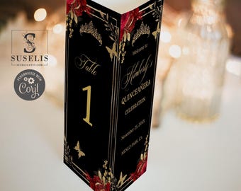 May include: A black triangular table card featuring gold and red floral accents, a gold tiara graphic, and gold butterflies. One side displays the text Table 1, while the other side reads Welcome to Kimberly's Quinceañera Celebration, November 25, 20XX, Menlo Park, CA.
