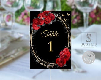 May include: A black table number card featuring the text Table 1 in gold script and block lettering. The design includes a gold oval frame, clusters of red roses with dark leaves, and small gold butterflies against a black background.