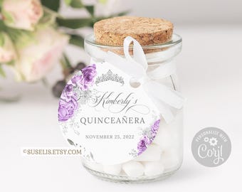May include: A clear glass jar filled with white candies, sealed with a cork stopper. A round white tag is tied to the neck with a white ribbon, featuring purple roses, a silver tiara graphic, and the text Kimberly's QUINCEAÑERA NOVEMBER 25, 2022.