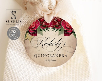 May include: A round tag with a cream-colored background featuring red roses, green leaves, and a small gold butterfly. The text reads Kimberly's QUINCEAÑERA 11.25.20xx in black script and serif fonts, attached to a light beige fabric drawstring pouch.