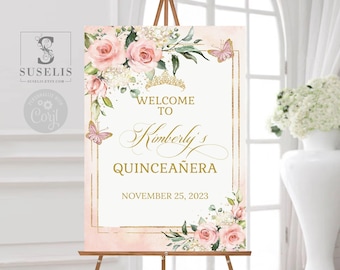 May include: A rectangular welcome sign featuring pink roses, green leaves, and butterflies. The text reads: WELCOME TO Kimberly's QUINCEAÑERA NOVEMBER 25, 2023. A gold crown icon sits above the text, framed by a thin gold border on a pale background.