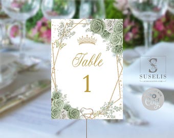 May include: A rectangular table number card featuring the text Table 1 in gold script and print. The design includes a gold geometric frame, a gold crown icon, and clusters of sage green roses and white floral accents on a white background.