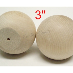 May include: Two unfinished wooden spheres, each measuring 3 inches in diameter. The spheres have a smooth surface and a small hole drilled through the bottom.