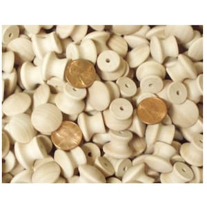 May include: A large pile of unfinished wooden knobs, some with a hole in the center, and some with a rounded top.  A few US pennies are scattered throughout the pile.