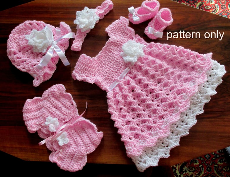 Puede incluir: Patr&oacute;n de ganchillo para un conjunto de beb&eacute; ni&ntilde;a, que incluye un vestido, un gorro, botines y una diadema. El conjunto es rosa con detalles blancos y presenta un dise&ntilde;o floral. "pattern only" est&aacute; escrito en la imagen.