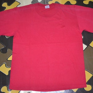 May include: A red short-sleeved t-shirt with a small embroidered logo on the left chest.