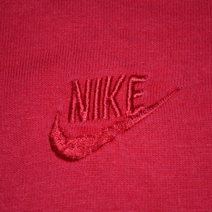 Può includere: Maglietta rossa con logo Nike ricamato in bianco.