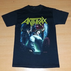 Puede incluir: Camiseta negra con un estampado gráfico de una banda llamada "Anthrax". El gráfico presenta a una persona con una chaqueta negra y una persona con una camisa blanca.
