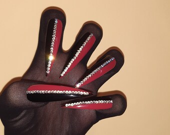 May include: A hand wearing black fishnet gloves with long, red, and black stiletto nails adorned with rhinestones.