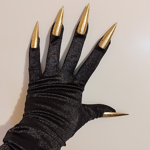 May include: Black satin gloves with long, pointed gold fingernails. The gloves are gathered at the wrist and extend to the elbow.