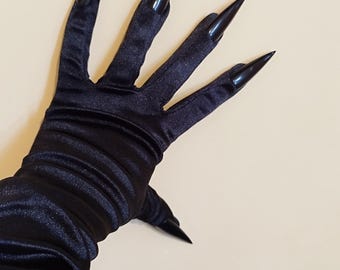 May include: Black satin gloves with long, pointed, black fingernails. The gloves are a dark, solid black colour and have a smooth, shiny texture. The fingernails are sharply pointed and extend beyond the fingertips.