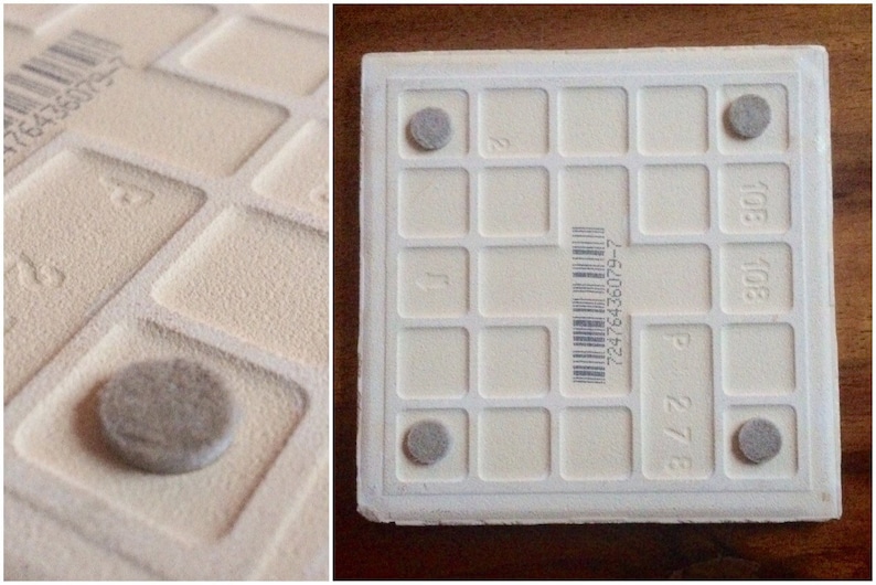 K&ouml;nnte beinhalten: Wei&szlig;e Keramikfliese mit einem Gittermuster und vier grauen Gummif&uuml;&szlig;en auf der Unterseite. Die Fliese hat einen Barcode und die Zahlen "27/8" und "108" sind darauf gedruckt.
