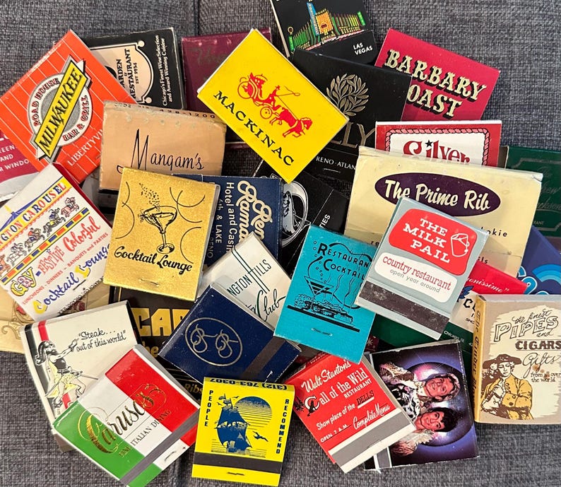 May include: A collection of vintage matchbook covers with various designs and text. The covers feature images of cocktails, restaurants, hotels, and other businesses. Some of the text includes "The Prime Rib", "The Milk Pail", "Barbary Coast", and "Cocktail Lounge".