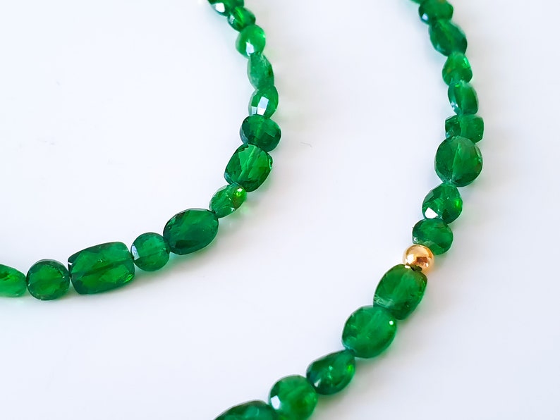 Pu&ograve; includere: Una collana di perle di pietre preziose verdi, ciascuna con una finitura sfaccettata, e un accento di perle dorate.