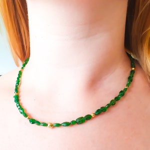 Pu&ograve; includere: Una collana di pietre preziose verdi con perline dorate. La collana &egrave; composta da piccole pietre verdi di forma ovale e perline dorate.