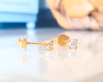 Könnte beinhalten: Ein Paar goldene Ohrstecker mit jeweils einem einzelnen runden Diamanten.
