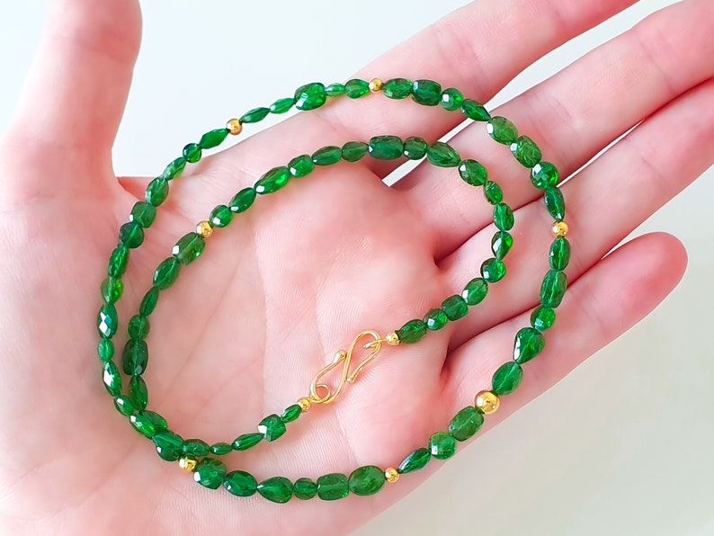 Pu&ograve; includere: Una collana di pietre preziose verdi con dettagli dorati. La collana &egrave; composta da perle ovali e ha una chiusura dorata.