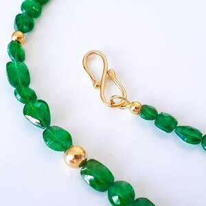 Pu&ograve; includere: Una collana di pietre preziose verdi con perline dorate e una chiusura dorata. La collana &egrave; realizzata con pietre preziose verdi di forma ovale.