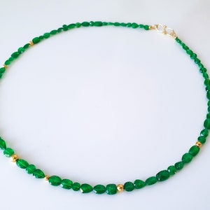 Pu&ograve; includere: Una collana di pietre preziose verdi con perline dorate. La collana &egrave; realizzata con pietre verdi di forma ovale e piccole perline dorate.