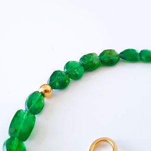 Pu&ograve; includere: Una collana di pietre preziose verdi con perline dorate. La collana &egrave; realizzata con pietre verdi sfaccettate di forma ovale.