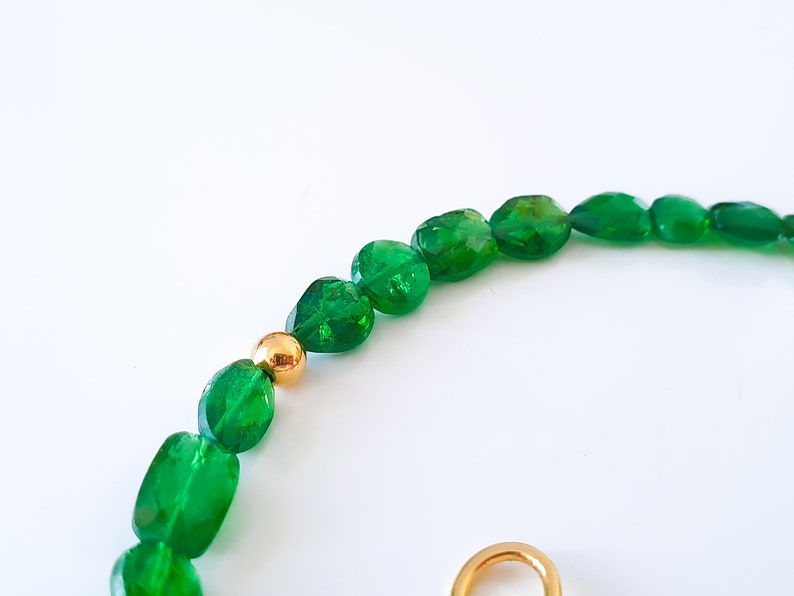 Pu&ograve; includere: Una collana di pietre preziose verdi con perline dorate. La collana &egrave; realizzata con pietre verdi sfaccettate di forma ovale.