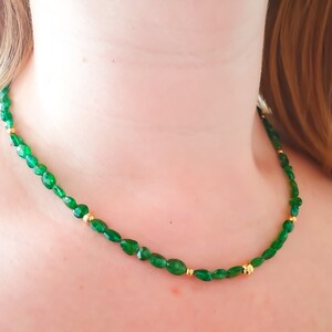Pu&ograve; includere: Una collana di pietre preziose verdi con perline dorate. La collana &egrave; composta da pietre verdi di forma ovale e piccole perline dorate.