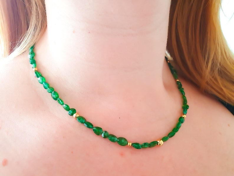 Pu&ograve; includere: Una collana di pietre preziose verdi con perline dorate. La collana &egrave; composta da pietre verdi di forma ovale e piccole perline dorate.