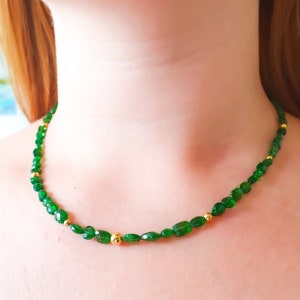 Pu&ograve; includere: Una collana di pietre preziose verdi con perline dorate. La collana &egrave; composta da pietre verdi di forma ovale e piccole perline dorate.