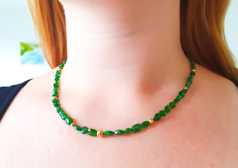 Pu&ograve; includere: Una collana di pietre preziose verdi con perline dorate. La collana &egrave; composta da pietre verdi di forma ovale e piccole perline dorate.
