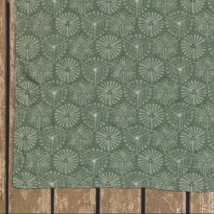 May include: A green fabric with a white floral pattern. The fabric has a repeating pattern of small white flowers.