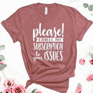 May include: A maroon t-shirt with the text "Please! Cancel my subscription to your issues" in white.