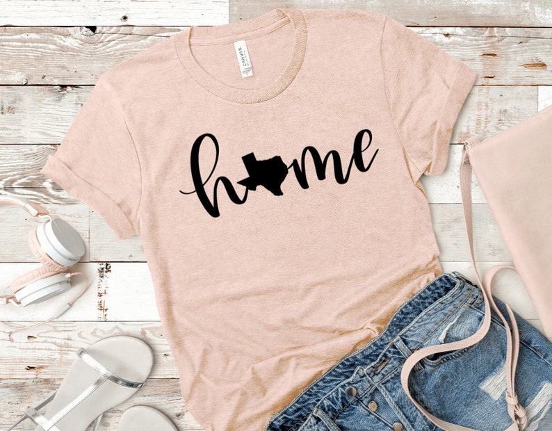 May include: A pink t-shirt with a black graphic of the state of Texas and the word "home" in cursive.