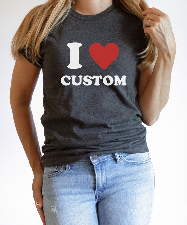 Puede incluir: Una camiseta gris oscuro con un gr&aacute;fico blanco que dice "Me encanta lo personalizado" con un coraz&oacute;n rojo.