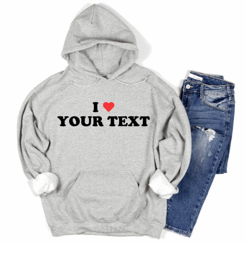 Puede incluir: Sudadera gris con capucha con un gr&aacute;fico negro que dice "I love YOUR TEXT" con un coraz&oacute;n rojo.