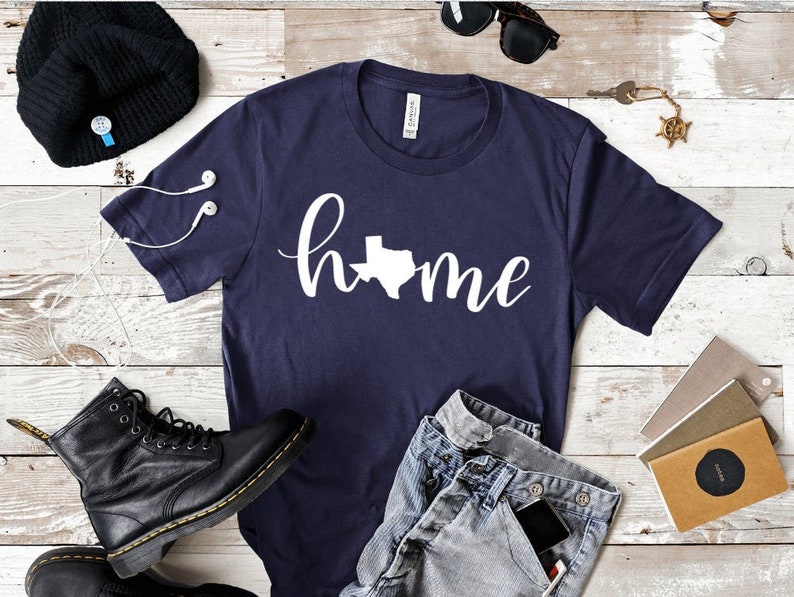 May include: A navy blue t-shirt with a white graphic of the state of Texas and the word "home" in a cursive font.