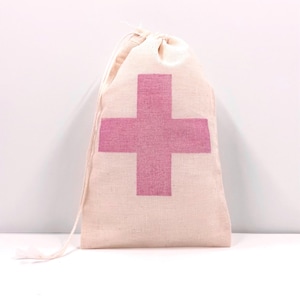 May include: A beige drawstring pouch made of a woven fabric featuring a large, centered pink cross graphic. The bag is closed at the top with thin, matching beige fabric cords that extend from the sides, creating a simple and functional storage item.