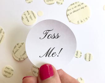 Puede incluir: Confetti blanco circular con texto negro que dice "Toss Me!" El confeti está siendo sostenido por una mano con esmalte de uñas rosa.
