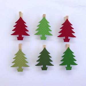 May include: Six Christmas tree-shaped clothespins with red, green, and lime green patterned paper. The clothespins are made of wood and have a natural finish.