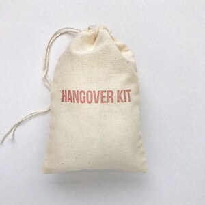May include: A small, white cotton drawstring bag with the words "HANGOVER KIT" printed in red on the front.