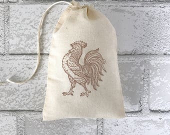 May include: A small, white cotton drawstring bag with a brown rooster design printed on the front.