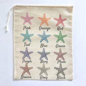 May include: A white canvas bag with 12 starfish printed on it. Each starfish is a different colour: pink, orange, red, teal, blue, green, purple, navy, plum, brown, grey, and black. The colours are written below each starfish.