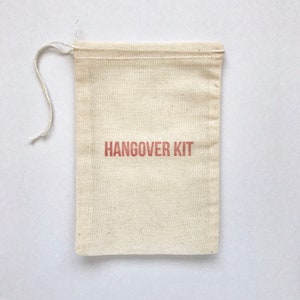 May include: A small, white cotton drawstring bag with the words "HANGOVER KIT" printed in red.