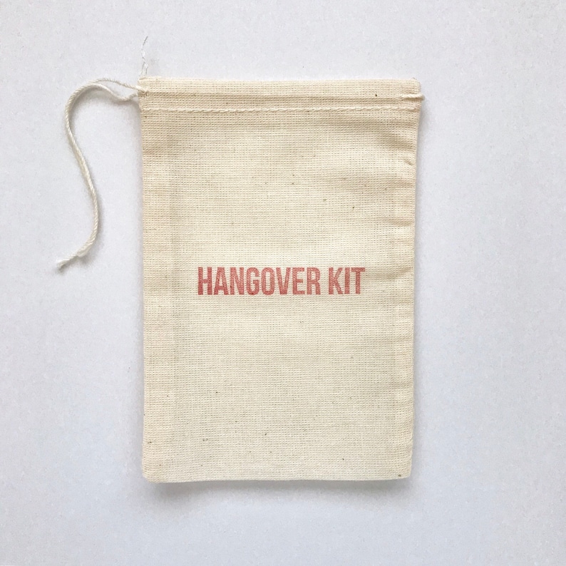May include: A small, white cotton drawstring bag with the words "HANGOVER KIT" printed in red.